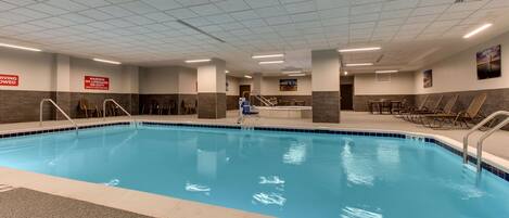 An indoor swimming pool with clear water, tiled walls, and a ceiling with fluorescent lighting.