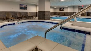 A spa area with a hot tub, seating area, and a pool.