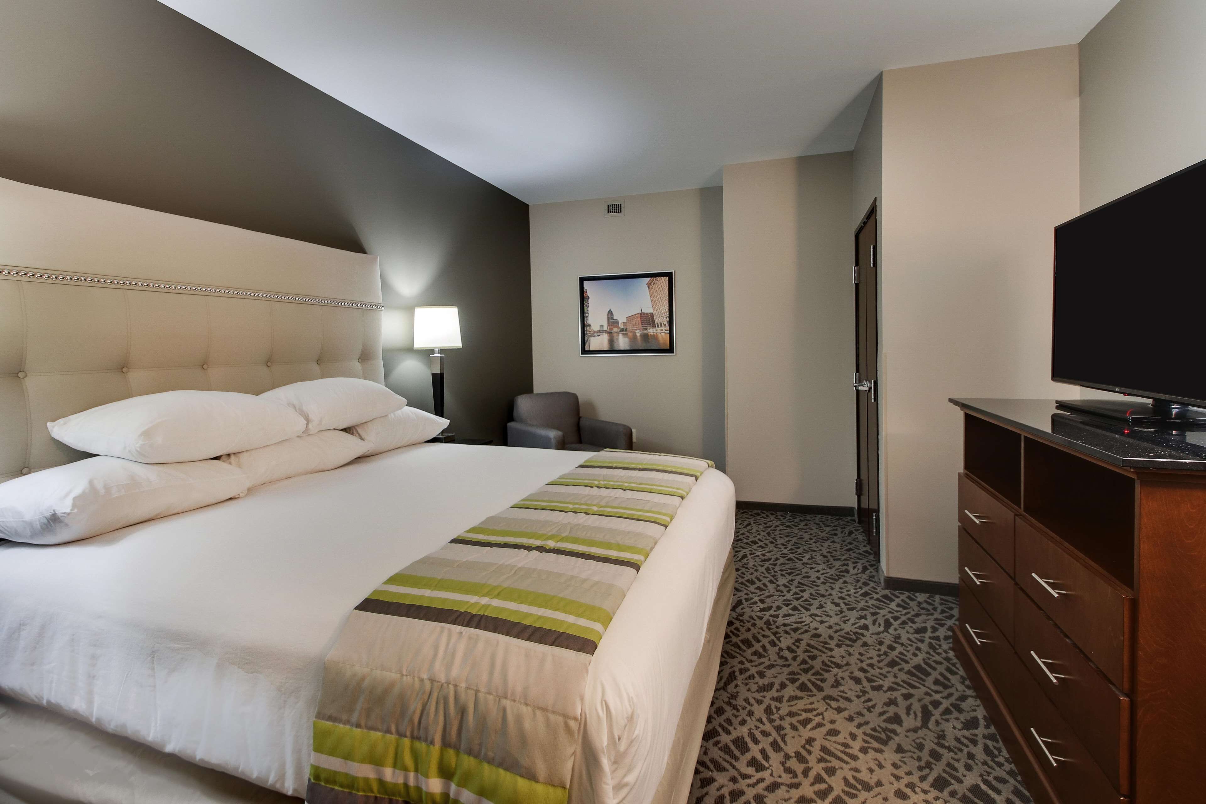 A hotel room with a large bed, a television, a desk, and a chair.