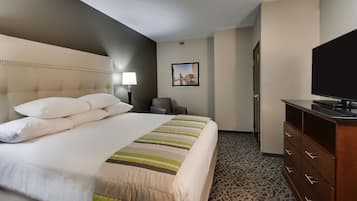 A hotel room with a large bed, a television, a desk, and a chair.