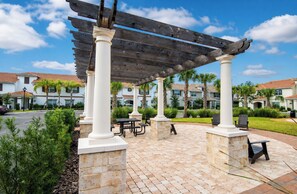A covered patio area with stone columns, picnic tables, and outdoor seating.