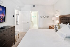A hotel room with a large bed, a dresser, a nightstand, a lamp, and a wall with decorative items.