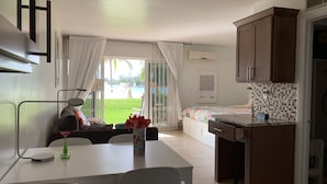 Habitación de hotel compacta con kitchenette, zona de comedor y puerta corredera de vidrio que da a una piscina.