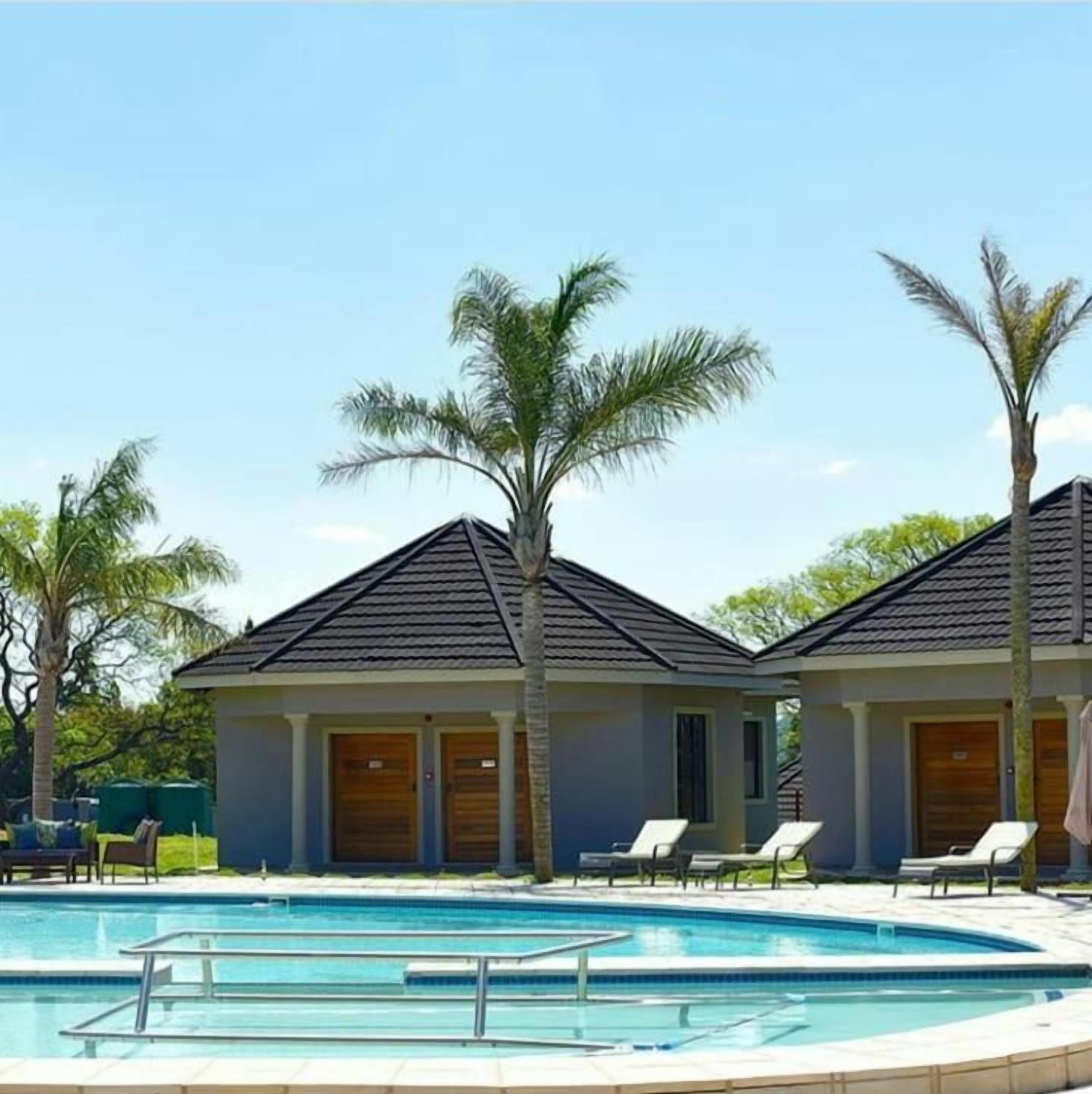 A swimming pool with lounge chairs and a building with a tiled roof.