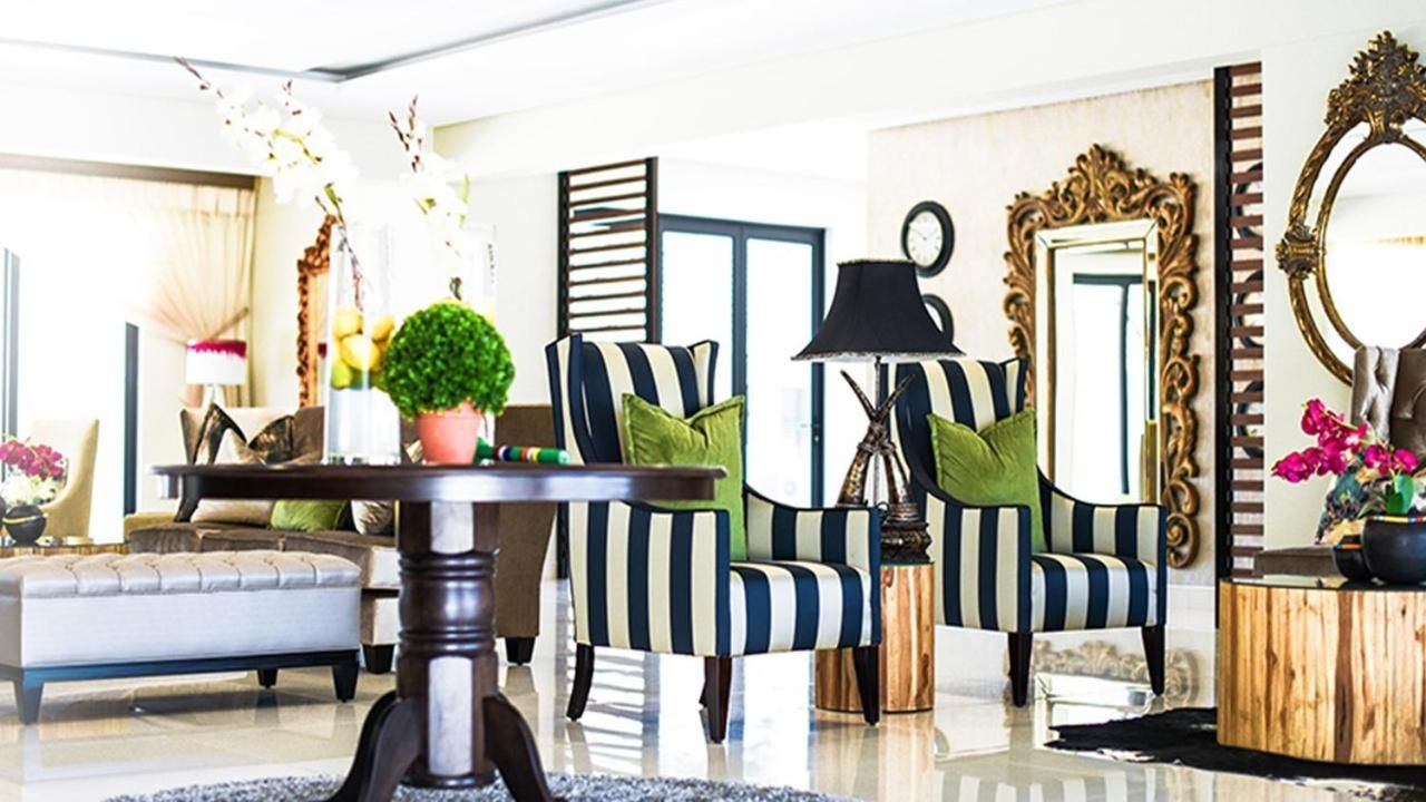Een moderne woonkamer met gestreepte fauteuils, een ronde salontafel en een bank.