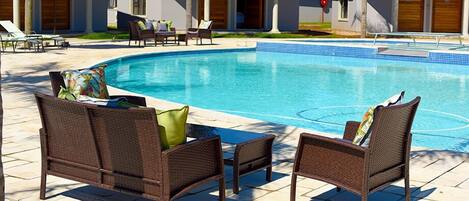 Una piscina con sillones de descanso y sombrillas.