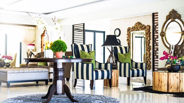 A modern living room with striped armchairs, a round coffee table, and decorative plants.