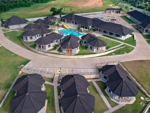 A residential area with multiple houses, a swimming pool, and a gated entrance. - Aloe Lifestyle Hotel (Eshowe)