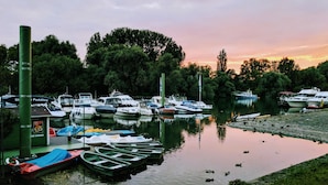 Ein Yachthafen mit verschiedenen Schiffen, umgeben von Bäumen und einer ruhigen Wasserfläche.