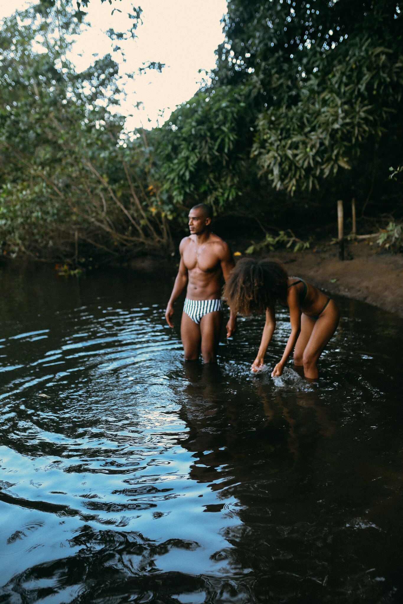 Dos personas de pie en el agua, rodeadas de vegetación densa.
