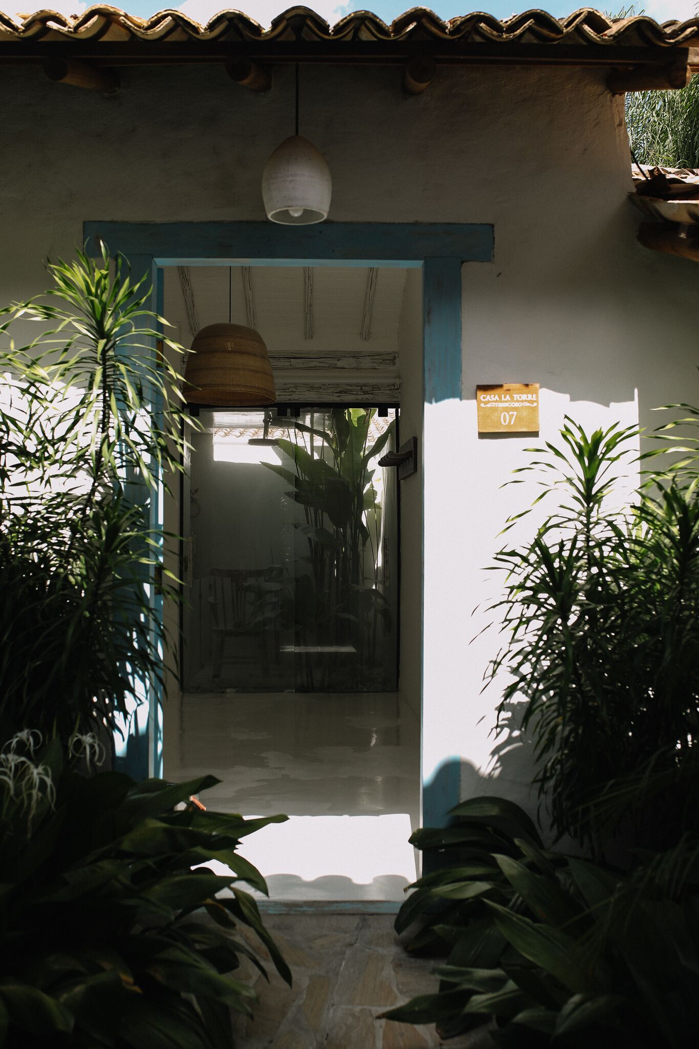 A doorway with a sign reading "Casa La Torre 07" leading into a room with a tiled floor and a hanging light fixture.
