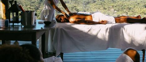 A massage therapy session in a wooden room with a scenic view.