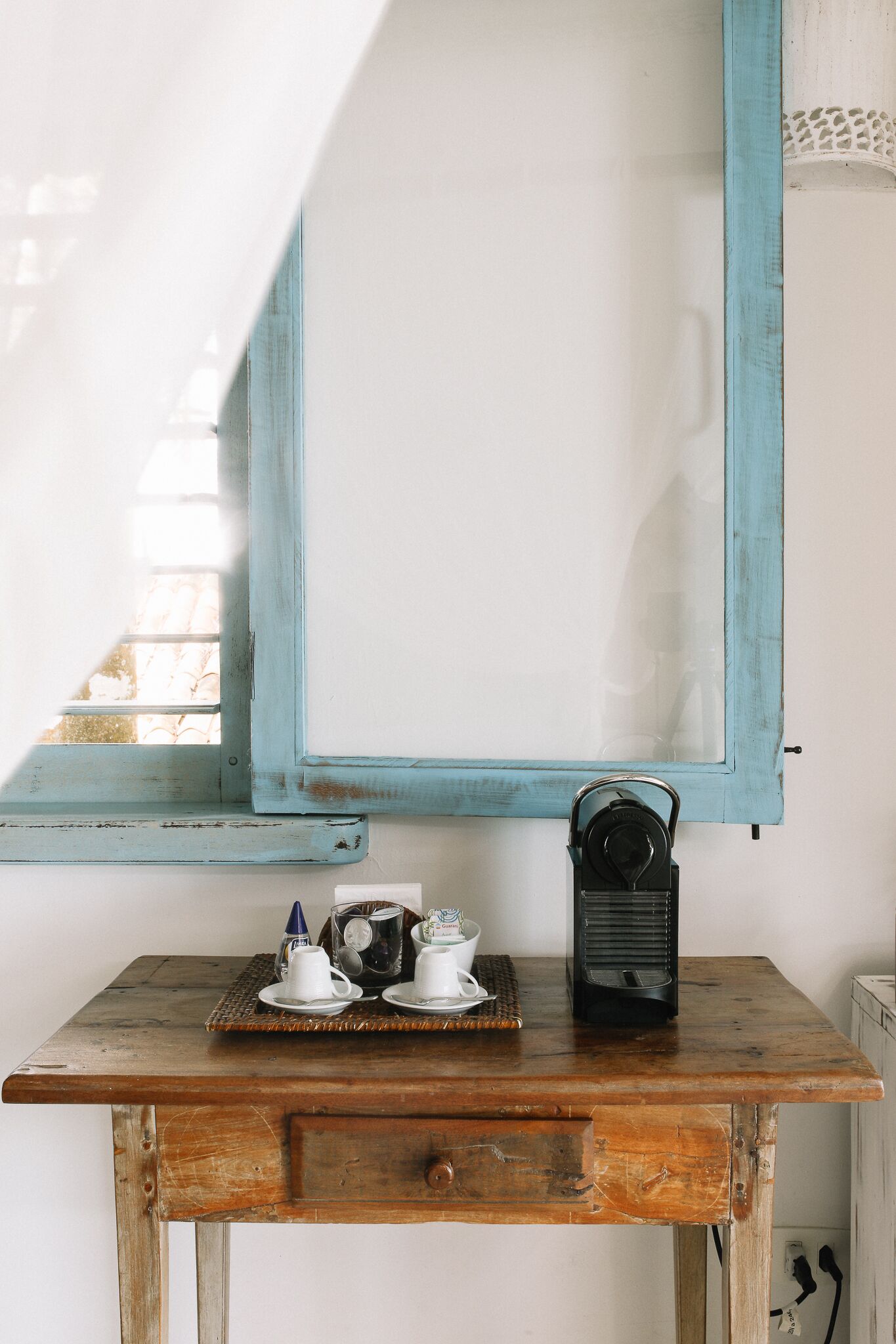 A rustic wooden table with a vintage radio, a tray with teacups, and a small decorative item.