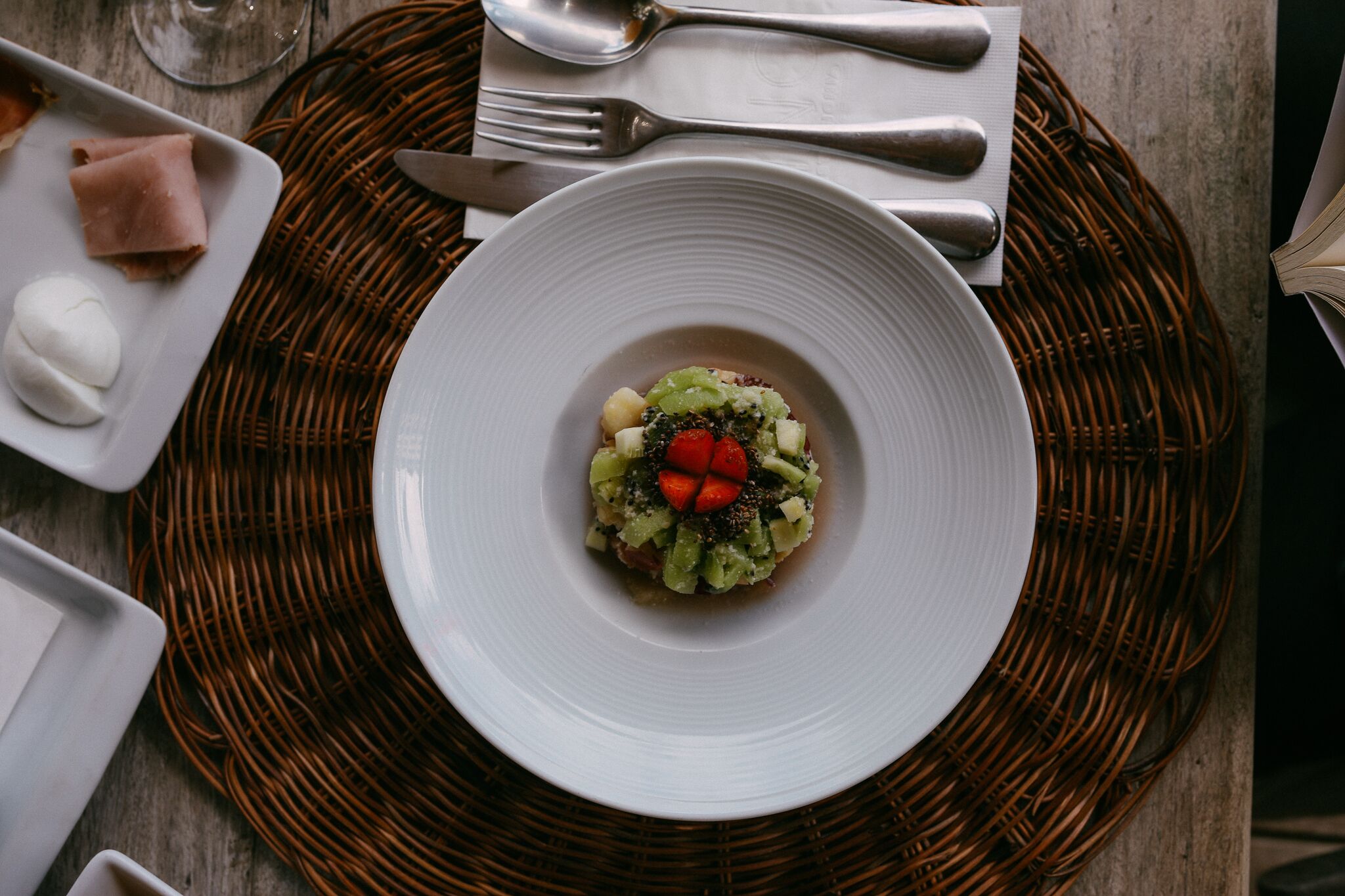 Une assiette blanche sur laquelle se trouve un plat, le tout posé sur un set de table en fibres tressées.