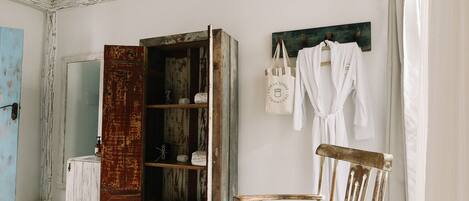 A rustic bathroom with a wooden chair, a hanging basket, and a shelf with toiletries.