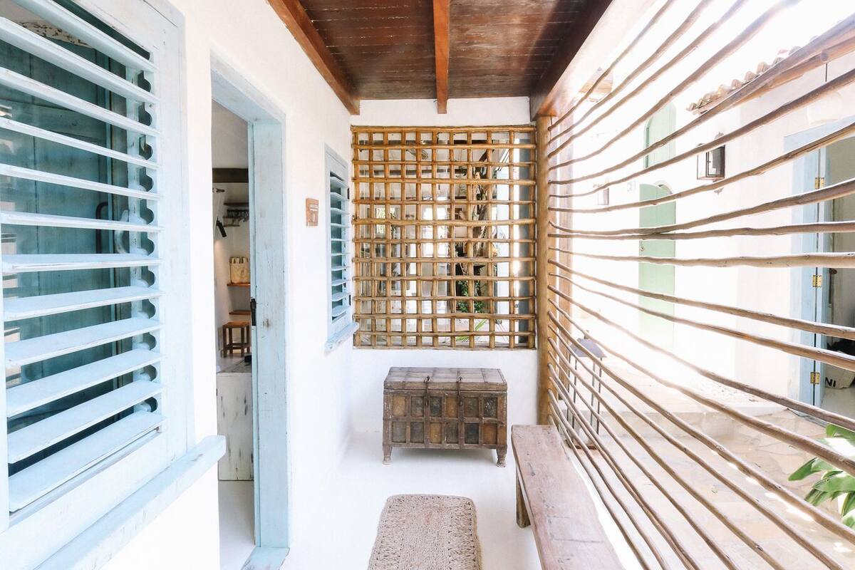 A corridor with wooden ceiling beams, a woven bench, and a lattice partition.