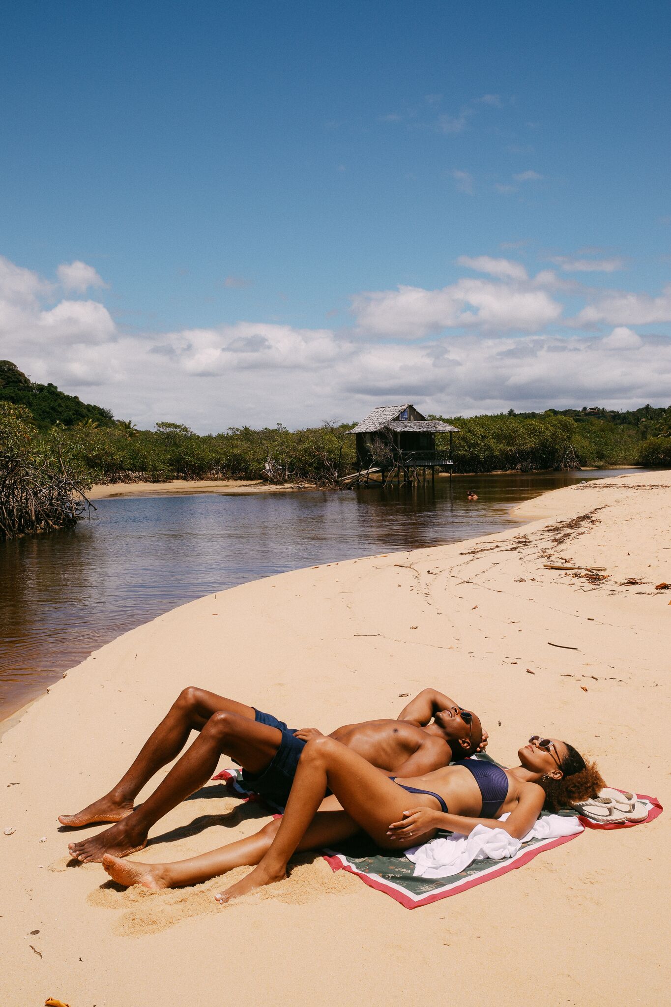 A beach scene with a hut and a river.