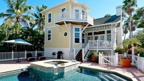 A two-story house with a pool, a covered patio, and a white fence.