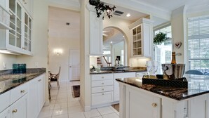 A spacious kitchen with white cabinetry, granite countertops, and a central island.