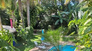 A pool surrounded by lush greenery and a wooden deck. - Wonderful house with 5 suites in Barra do Sahy. (Praia Barra do Sahy)