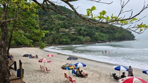 A beach with umbrellas, chairs, and people. - Wonderful house with 5 suites in Barra do Sahy. (Praia Barra do Sahy)