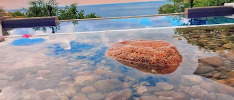 Una piscina cristalina con rocas visibles y vista al océano.