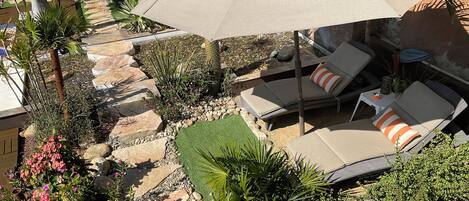 A patio area with outdoor seating, umbrellas, and a variety of plants.