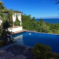 Una piscina al aire libre, sombrillas, sillones reclinables de piscina