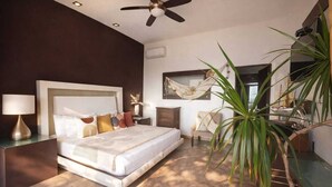A bedroom with a bed, bedside tables, a ceiling fan, a hammock, a chair, and a large plant. - Casa Qi Mazunte (Santa María Tonameca)