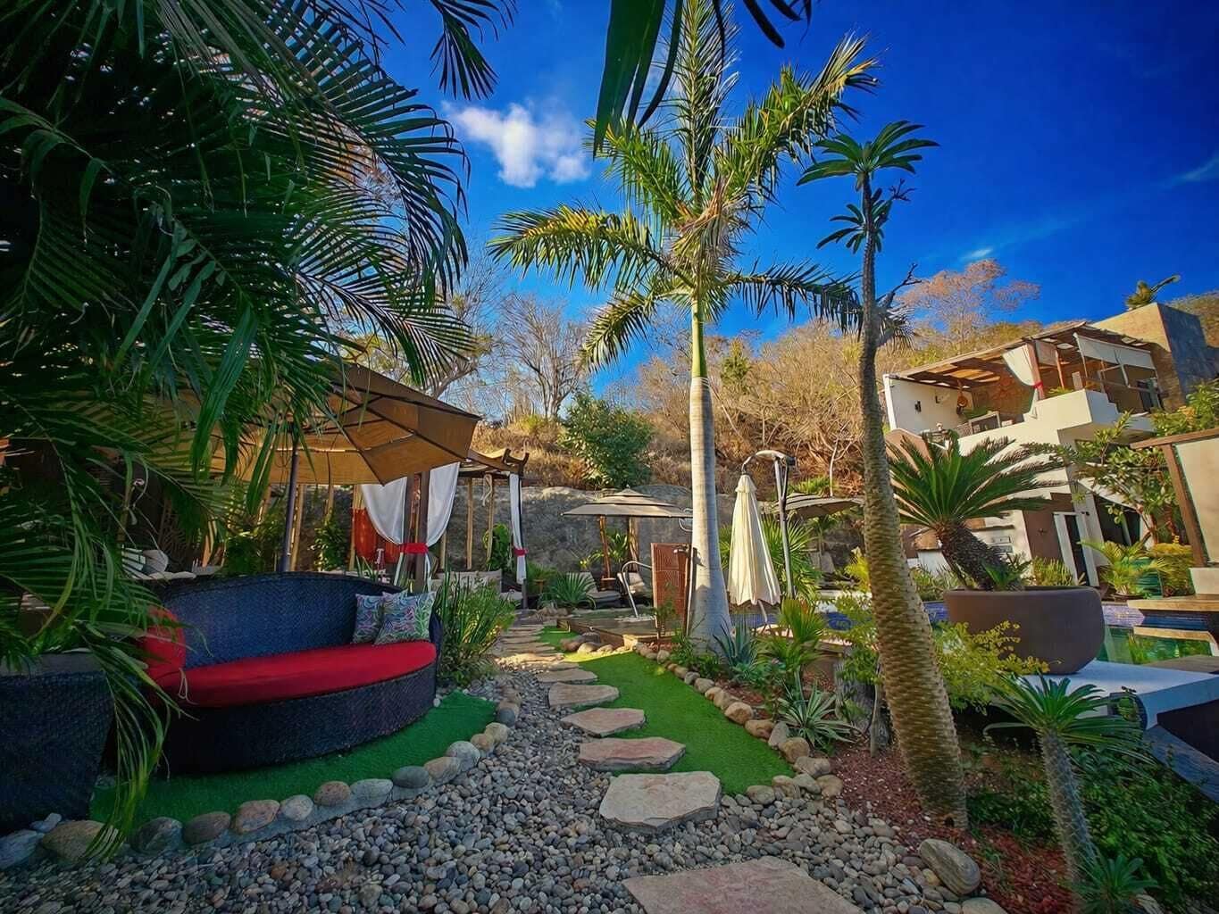 A garden with a circular seating area, a pathway, and palm trees.