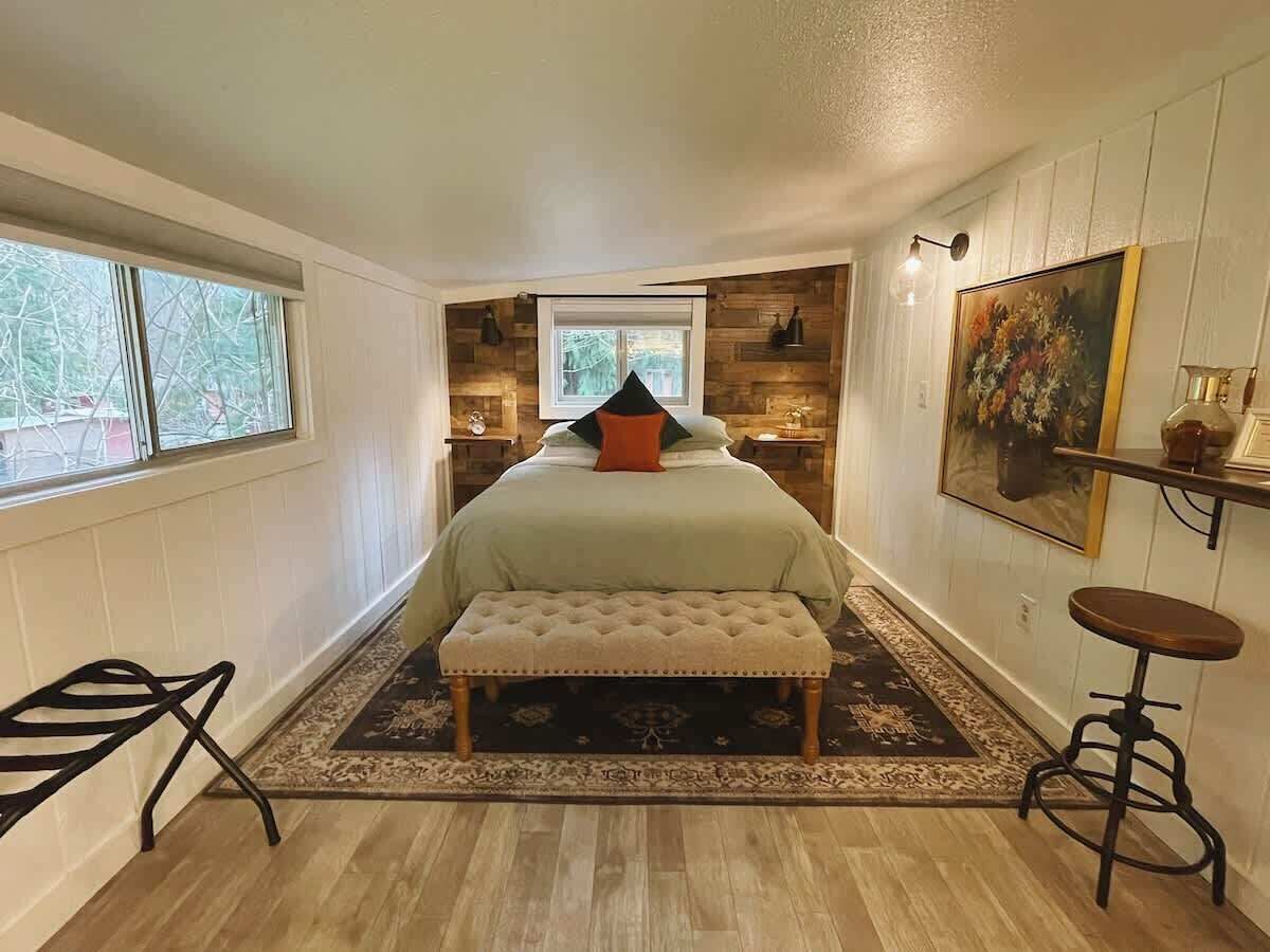 A bedroom with a bed, bench, and a small stool.