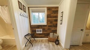 Ein Badezimmer mit Holzboden, Duschvorhang, Handtuchhalter, Fenster und Tür.