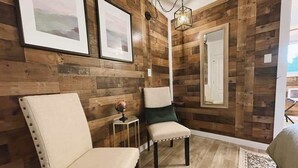 Ein Zimmer mit Holzwandverkleidung, zwei Polsterstühlen, einem kleinen Beistelltisch mit Globus und einer Pendelleuchte.