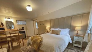 Ein geräumiges Schlafzimmer mit einem großen Bett, Nachttischen, einem Schreibtisch und einem Sessel.