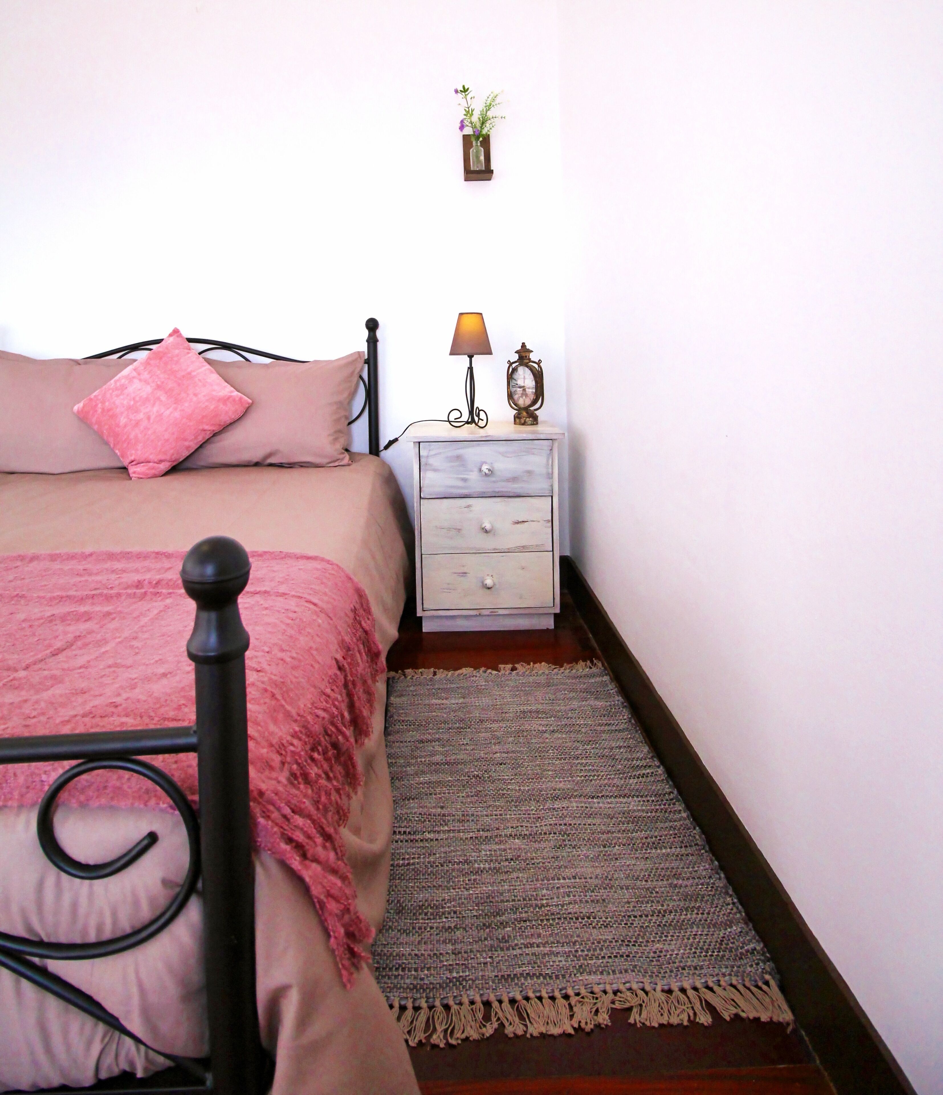 Une chambre à coucher avec un lit, une table de chevet, une lampe et une petite plante.