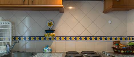 A kitchen with wooden cabinets, a granite countertop, a stainless steel sink, a stove, and a decorative backsplash.