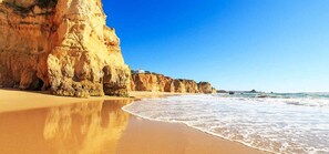 A beach with a large cliff and a building on top. - Minuet Apartment, Pool (Portimão)