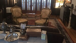 A traditional room with two ornate chairs, a table set with silverware, and a chandelier. - Edgewood Manor (Providence)