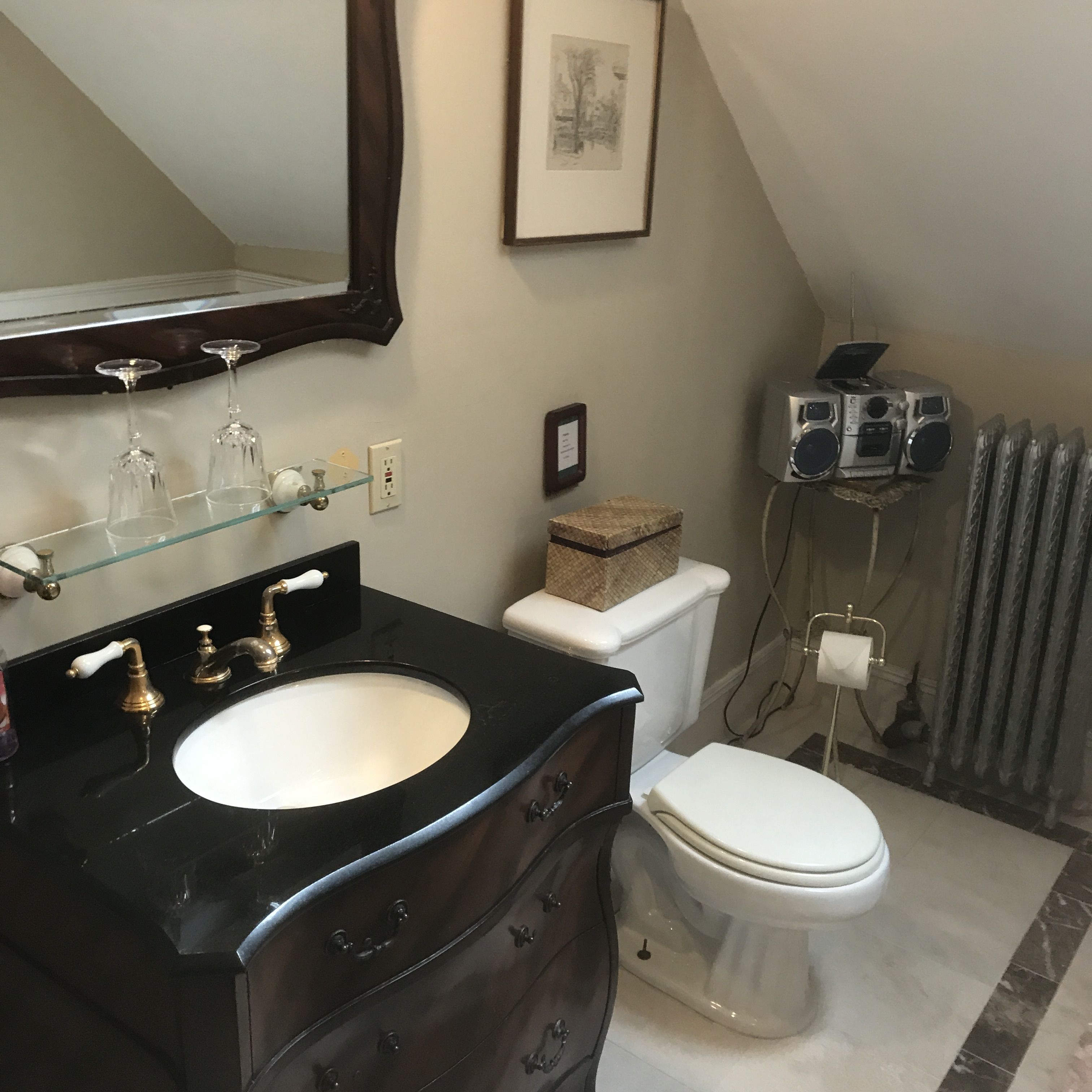 A bathroom with a black vanity, a white sink, a toilet, and a framed picture on the wall.