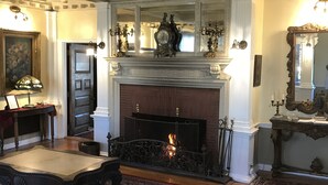 A room with a fireplace, a mirror, and a patterned rug. - Edgewood Manor (Providence)