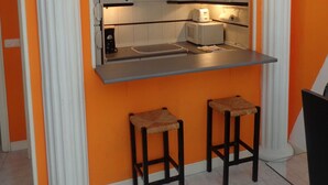 A compact kitchen with white cabinetry, a built-in countertop, and two stools. - GOYA-APARTMENT-ARTS (Madrid)