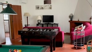Un salon confortable avec une table de billard, un canapé, un téléviseur et une cheminée.