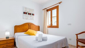Una camera da letto con un letto di legno, un comodino con una lampada, una finestra con tende e un’opera d’arte appesa al muro.