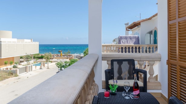 Un balcone con un tavolo apparecchiato per due, vista piscina e mare.