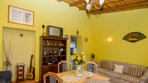 A living room with a wooden ceiling, a television on a shelf, a sofa, a dining table with chairs, and a vase with flowers. - Flynn Villa, BBQ, Garden (Silves)