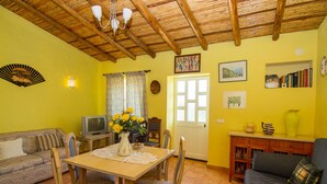 A cozy living room with a wooden ceiling, a dining table with chairs, a sofa, a television, and a bookshelf. - Flynn Villa, BBQ, Garden (Silves)