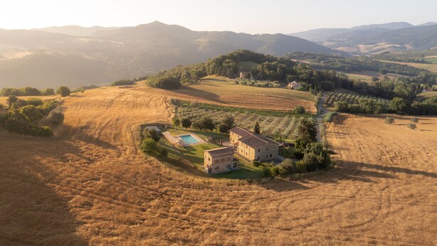 Una finca rural con piscina, edificios de piedra y extensos campos.