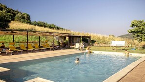Una piscina con tumbonas y una zona de estar cubierta.