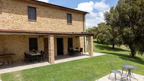 Un edificio de piedra con un patio techado y mobiliario para exteriores.