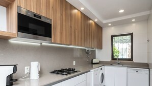 A modern kitchen with a built-in oven, a gas stove, a washing machine, and a dishwasher. - Feta Villa, Pool, BBQ (Olhos de Água)
